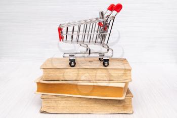 Shopping cart on the books. Buying or selling books concept.