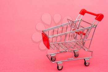 Empty shopping cart on pink background. Purchase or marketing concept