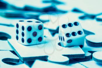 Dice on the pile of jigsaw puzzles, blue toned image
