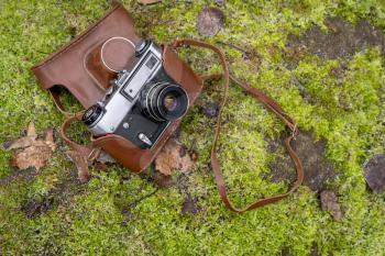 Retro camera on the mossy stone background. Traveling with photo camera, photography as hobby concept