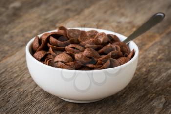 Bowl with chocolate flakes on dark wooden background
