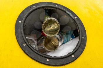 Close-up hole of yellow garbage bin for plastic and metal recycling