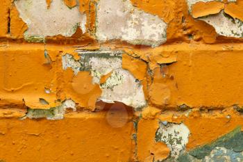 Brick wall with peeling orange paint