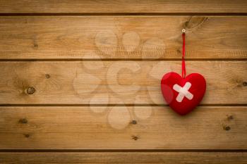 Wounded heart with bandage hanging on the wooden wall