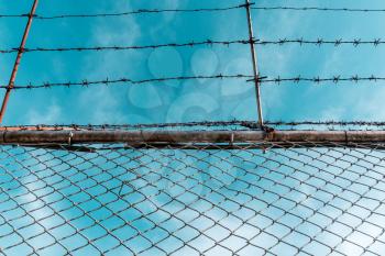 Metal fence with barbed wire and blue sky