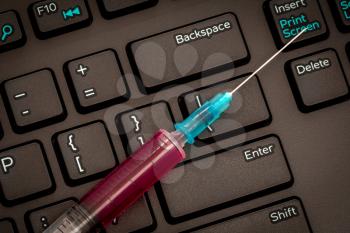 Black keyboard and syringe.Computer virus protection. The concept of digitalization in medicine. Workplace of a modern doctor.