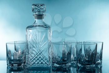 Antique glass whiskey bottle and a glasses on the blue background