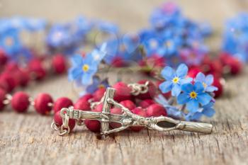 Rosary and blue forget-me-nots flowers. Religion concept.