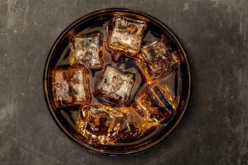 Glass of cola with ice cubes, close-up, top view.