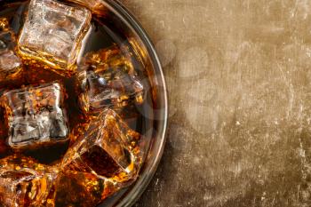 Glass of alcohol coctail or cola with ice cubes, close-up, top view. Copy space.
