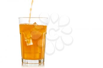 Orange juice is poured into a glass with ice cubes. Isolated on white background.