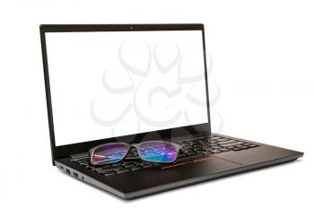 Eyeglasses on the black laptop, isolated on white background. Copy space.