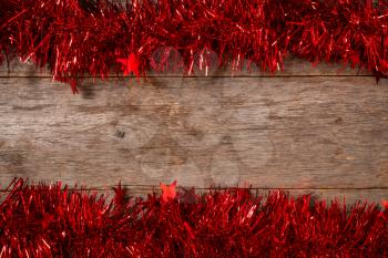 Brown wooden board with red tinsel frame. Copy space.