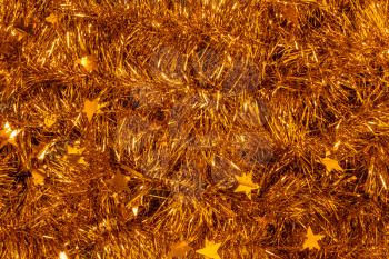Scattered shiny festive tinsel of golden color. Celebratory Christmas gold texture.