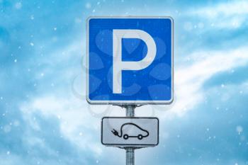 Electric car charging station sign on the snowy sky background 