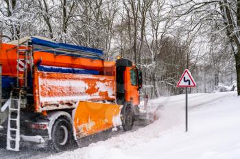 Snow ploughing truck cleans the road. Country road after heavy snowfall.