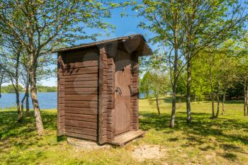 Wooden professionally repaired outhouse in a green park serves as a toilet in nature