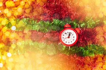 Alarm clock show last minute before midnight with ornaments for Christmas or New year and blur light background