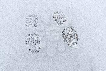 Top view of footprint on snow covered ground. Shoeprints in snow - danger walking in the snow.