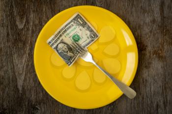 Economic crisis. One paper dollar with a fork  on a yellow plate. Dividing the budget. Concept of the global financial crisis. Lack of money for food.