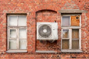Outdoor air conditioning unit on the facade of a old brick house