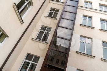 Glass elevator on a multistorey house facade. An example of living solution for persons with walking disability.