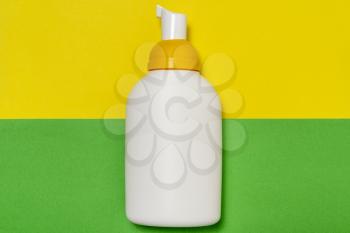 Plastic white bottle with dispenser pump  on colored background 
