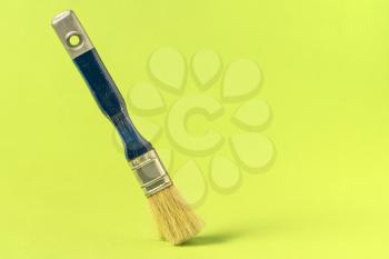 Paint brush stands on the green background, copy-space