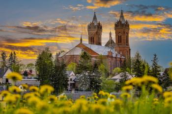 Yellow dandelions on foreground and church with bell towers on the sunset