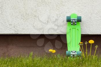 Green skateboard leaning against wall. Skateboard in the modern space. Copy space.
