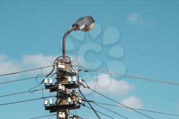 Concrete pylon with wires and street lamp on the sky background