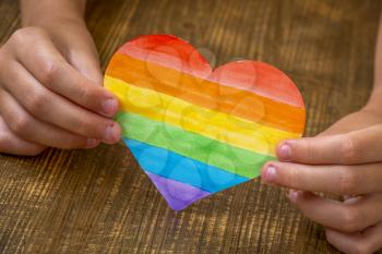 A child holds a multicolored heart in hands, the concept of lgbt friendly