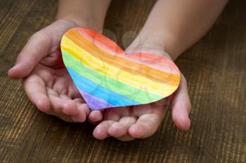 Girl holds a multicolored heart in hands, the concept of lgbt friendly and tolerance