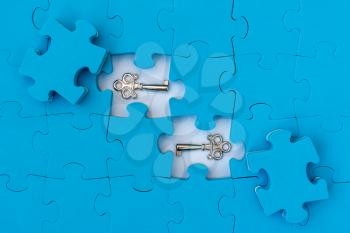 Find key of of solution. Blue jigsaw puzzle with small metal keys.