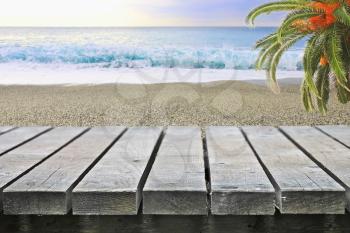 Wooden table near ocean beach with palm