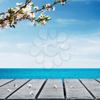 Wooden table near sea with cherry branch