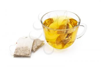 Green herbal tea from a bag in a glass cup, two sachets of herbal tea isolated on a white background