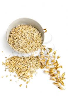 Rolled oats in a bowl on the table in the form of hearts, ripe stalks of oats isolated on a white background