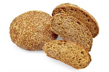 The whole round and cut into slices of rye bread rolls with sesame seeds isolated on a white background