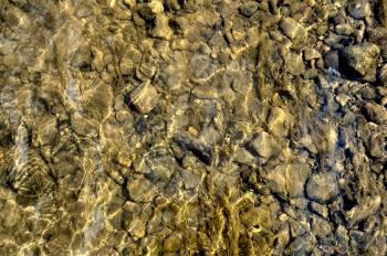 The texture of the large and small stones on the river bottom and the reflection on the water surface