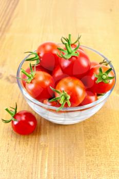 Small tomatoes in a glass bowl on a wooden table