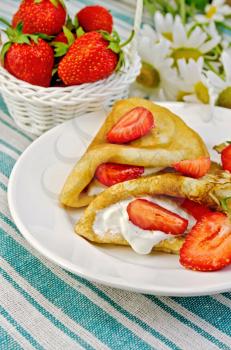 Two pancakes with strawberries and cream, a basket of berries, bouquet of daisies on a striped linen napkin
