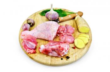 Chicken leg cut on a round board with garlic, parsley, ginger and a knife isolated on white background