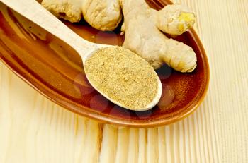 Roots of fresh ginger, a wooden spoon with a powder of ginger on pottery against a wooden board