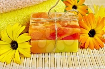 Two bars of homemade soap, towels, marigold flowers on a background of bamboo napkins