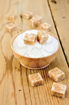 Cubes of brown sugar and white sugar in a wooden bowl on a wooden table