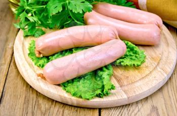 Sausage with parsley and lettuce on a wooden boards background