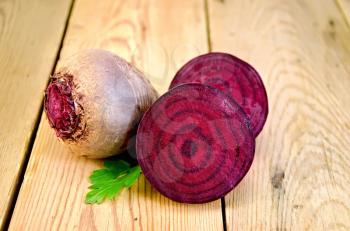 Beets whole and cut with leaf parsley on a wooden boards background