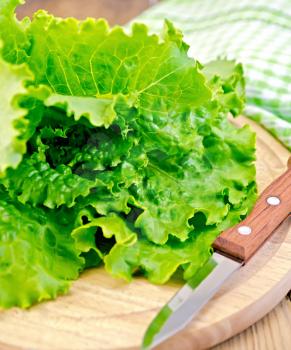 Green lettuce with a knife, a napkin on a wooden boards background