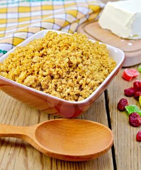 Brown cheese cooked in a square bowl, napkin, wooden spoon, colorful candied fruit, butter on wood board background